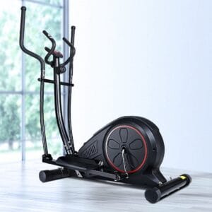 modern elliptical exercise machine with black frame and red flywheel ring, dual vertical handlebars and foot pedals, placed on light wooden floor near large windows with greenery outside