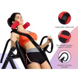 woman using inversion table with adjustable safety belt, removable lumbar support cushion, padded U-frame handles, and red foam rollers near shoulders for spinal decompression and back relief
