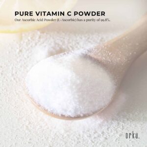 Wooden spoon filled with white crystalline Vitamin C powder resting on background of loose powder, partial lemon slice in upper left corner, promotional text highlighting 99.8% purity of L-Ascorbic Acid, branded with orku logo