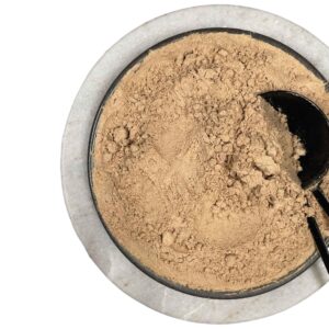 Ceramic bowl filled with finely ground light brown maca powder, black scoop partially buried in powder, placed on white surface, showcasing natural texture and serving presentation of this energizing root supplement