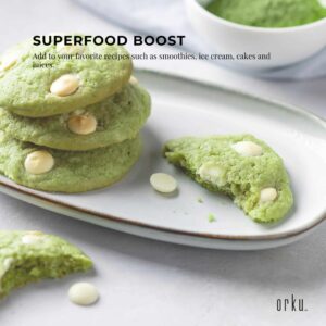 Orku matcha usage scene with plate of green cookies containing white chocolate chips, one broken to show interior, bowl of green powder in background, and text promoting superfood boost for smoothies, cakes, and juices