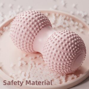 Pink peanut-shaped duo-massage ball with rounded textured bumps placed on light pink tray surrounded by translucent beads, with overlay text Safety Material