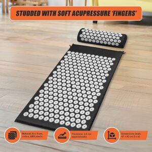 Black acupressure mat and cylindrical pillow with white spike discs on wooden floor; inset text highlights soft acupressure fingers and eco foam material