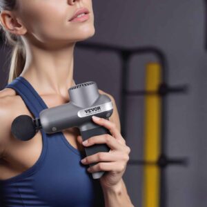 Person in blue athletic top using VEVOR massage gun on upper chest, with gym equipment in background, demonstrating muscle recovery application
