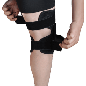 Close-up of leg wearing black knee brace; person fastening lower strap for secure orthopedic support