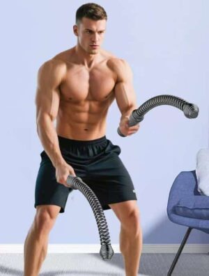 Shirtless man performing strength and cardio training with black cordless battle ropes in a squatting stance indoors