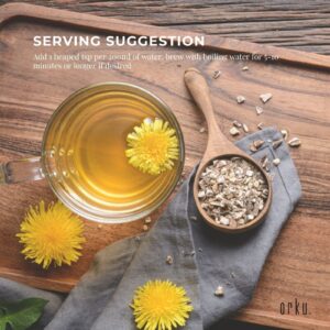 Glass of golden dandelion root tea with fresh dandelion garnish, wooden spoon, bowl, and rustic cloth