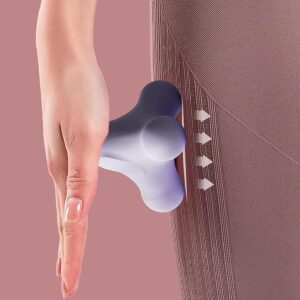 Close-up of a handheld, three-pronged massage tool in a light purple color being pressed against the side of a person’s leg. The tool features rounded nodes designed for targeted trigger point therapy, applying pressure to muscles through fabric. White directional arrows indicate the massage pressure being applied inward. The background is a soft pink tone, highlighting the tool’s ergonomic shape and use for muscle relaxation.