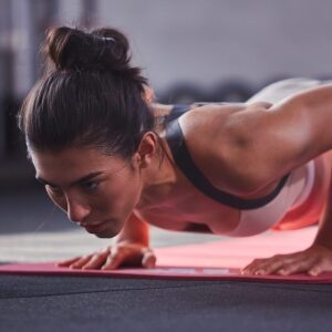 Woman performing push ups on Adidas 7mm fitness mat with cushioned non-slip surface for strength training, yoga and floor exercises