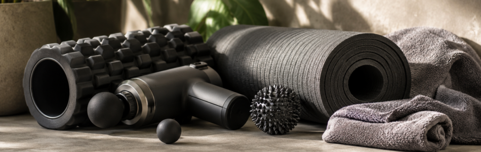 Recovery tools including a foam roller, massage gun, massage balls and exercise mat used to support muscle recovery after exercise
