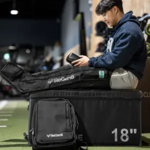 Person using ReGen8 Nyx compression recovery boots while seated