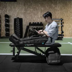 Person using ReGen8 Nyx compression boots with handheld controller