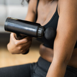 Close-up of a person using the Remology massage gun on their upper arm
