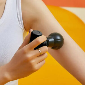 Person using Remology mini massage gun on upper arm